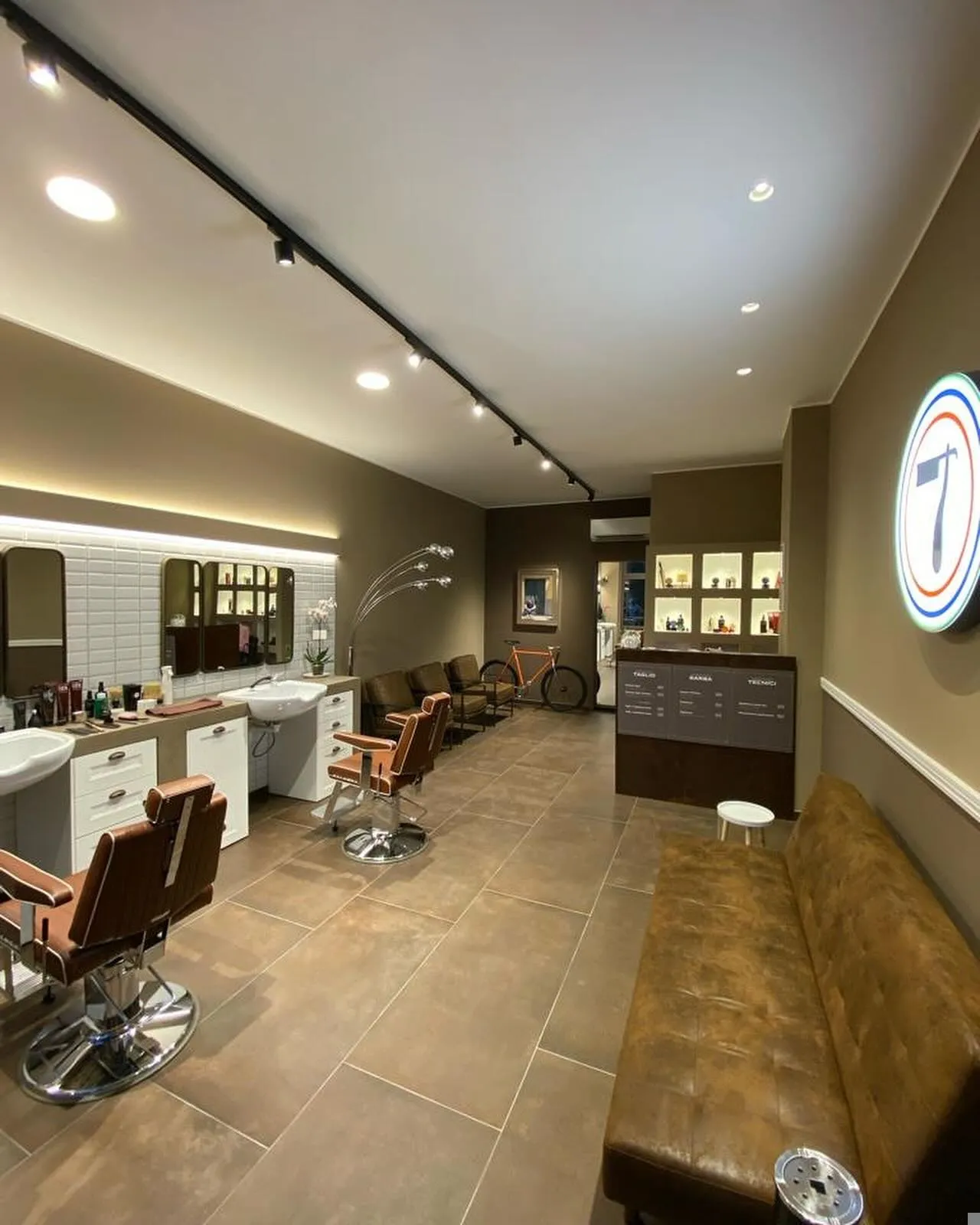 Barber shop con poltrone in pelle, specchiere e illuminazione a binario
