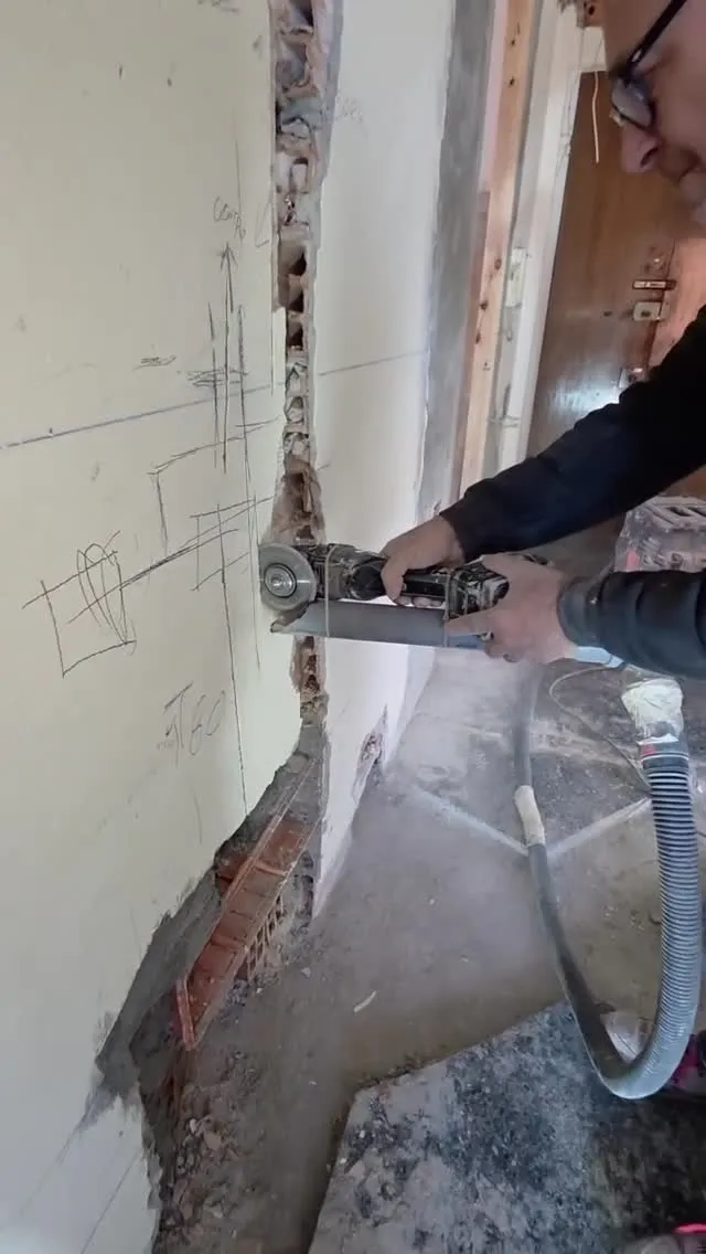 Operaio al lavoro con il flessibile su una parete durante la demolizione